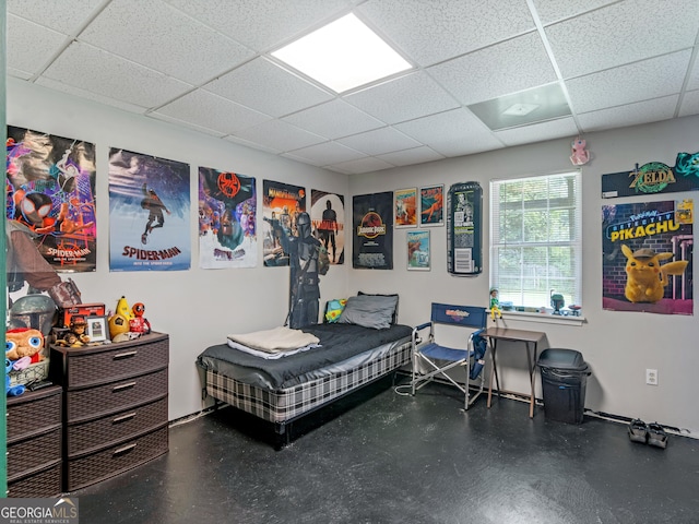 bedroom featuring a drop ceiling and finished concrete floors