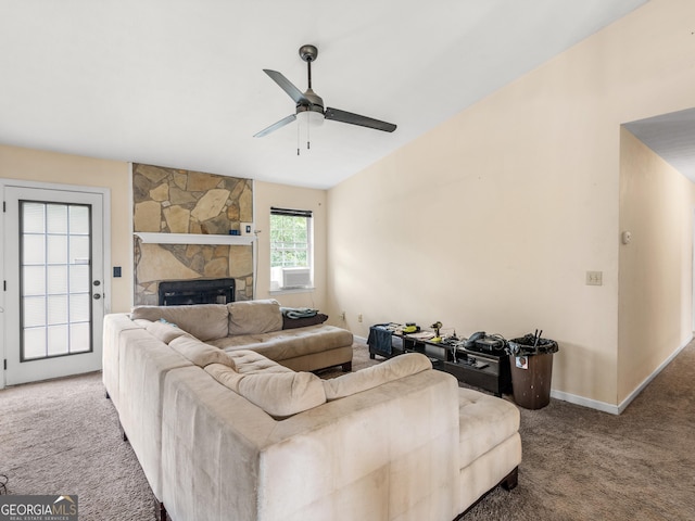 living room featuring carpet floors, lofted ceiling, baseboards, a stone fireplace, and ceiling fan