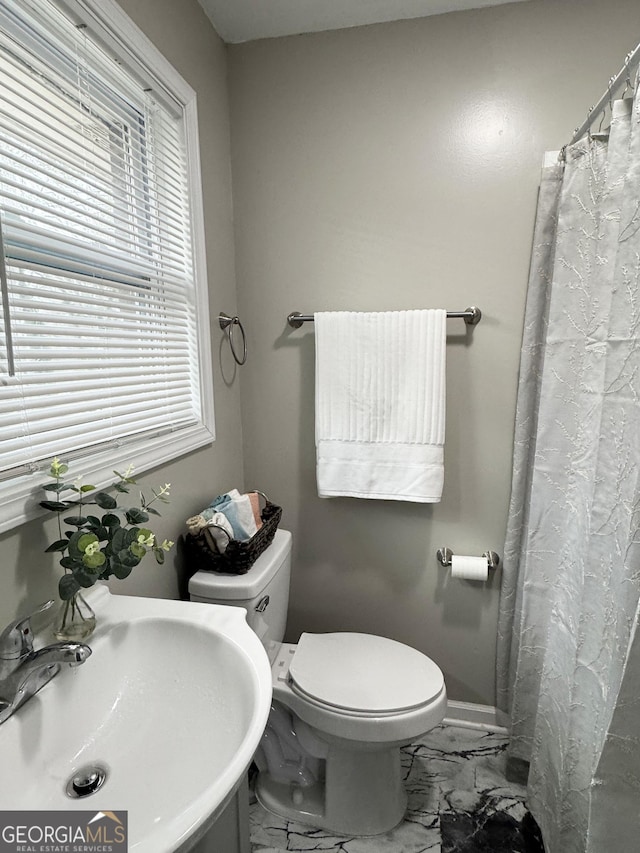 bathroom with marble finish floor, curtained shower, toilet, baseboards, and a sink
