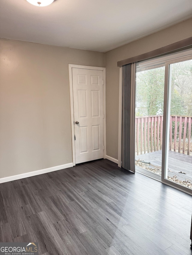 empty room featuring baseboards and dark wood finished floors