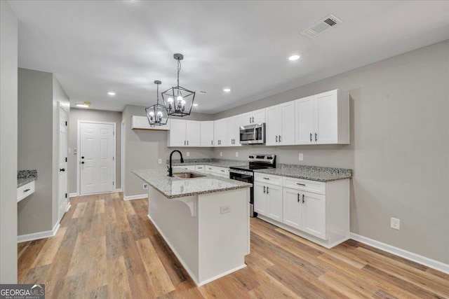 327 Peach Cir, Fort Valley, GA 31030 - kitchen featuring appliances with stainless steel finishes, white cabinetry, a chandelier, light wood finished floors, and light stone counters