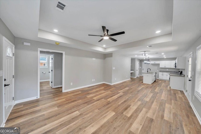 327 Peach Cir, Fort Valley, GA 31030 - unfurnished living room with a tray ceiling, ceiling fan, recessed lighting, and light wood finished floors