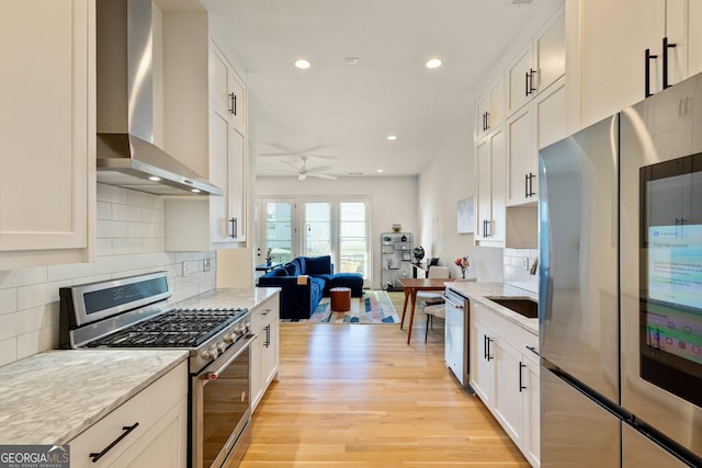 686 Exchange St SE, Atlanta, GA 30315 - kitchen featuring light wood-style floors, open floor plan, ceiling fan, wall chimney exhaust hood, and stainless steel appliances