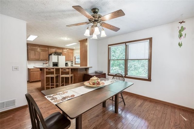 dining room with baseboards, a ceiling fan, wood finished floors, and visible vents
