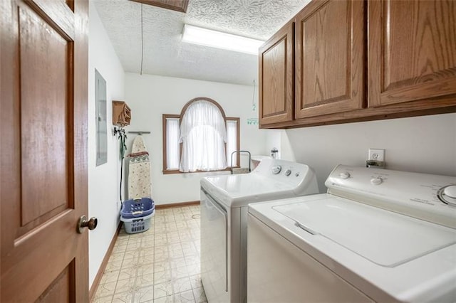 laundry area featuring baseboards, light floors, washer and clothes dryer, a textured ceiling, and cabinet space