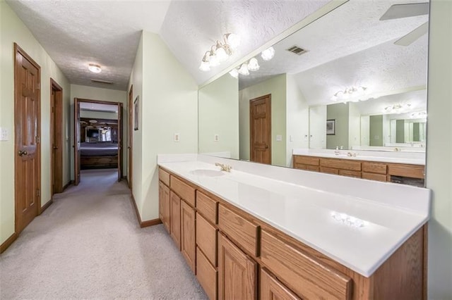 full bath with baseboards, vanity, a textured ceiling, and visible vents