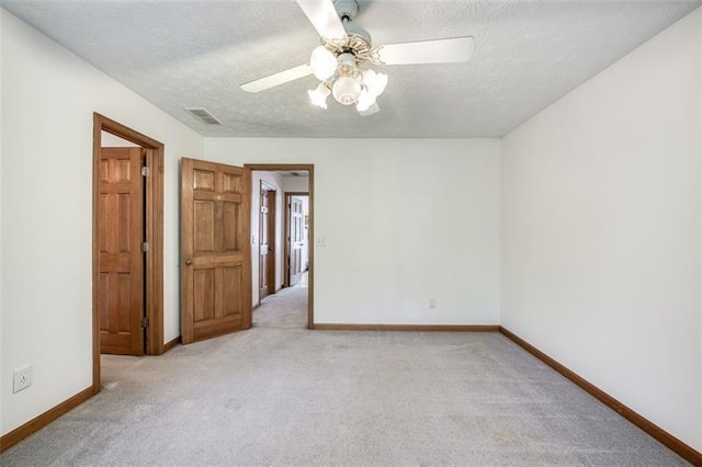 unfurnished room with ceiling fan, light colored carpet, baseboards, and visible vents