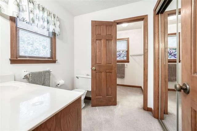 bathroom featuring vanity, plenty of natural light, baseboards, and toilet