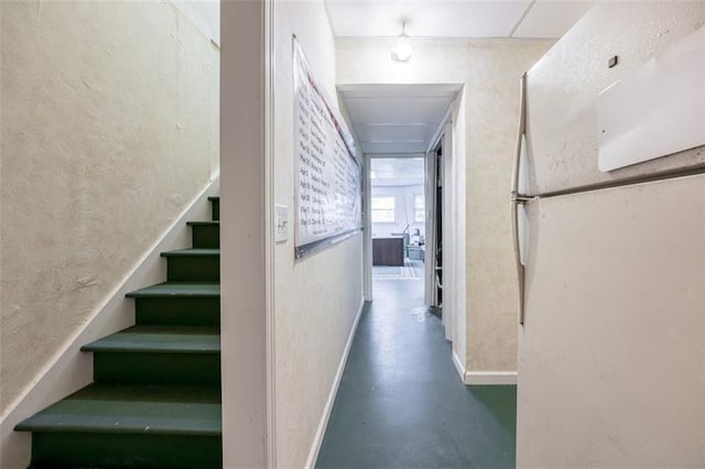 corridor with baseboards, stairs, and concrete flooring