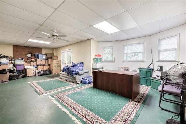 miscellaneous room featuring a ceiling fan, a paneled ceiling, and finished concrete flooring