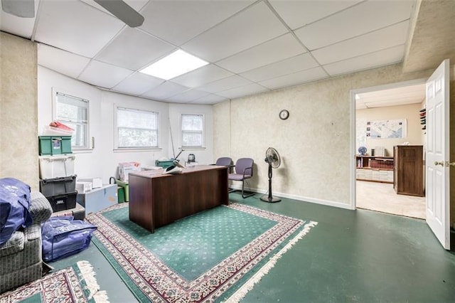 office space featuring finished concrete flooring, baseboards, and a paneled ceiling