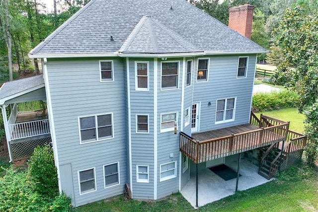 rear view of house featuring a lawn, a patio, a chimney, and a deck