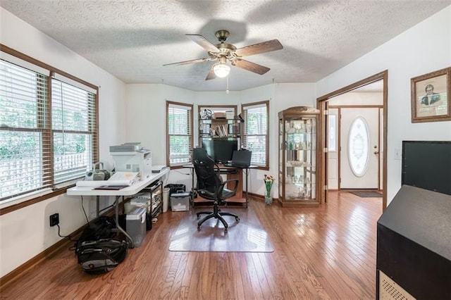 office area with baseboards, a textured ceiling, ceiling fan, and wood finished floors
