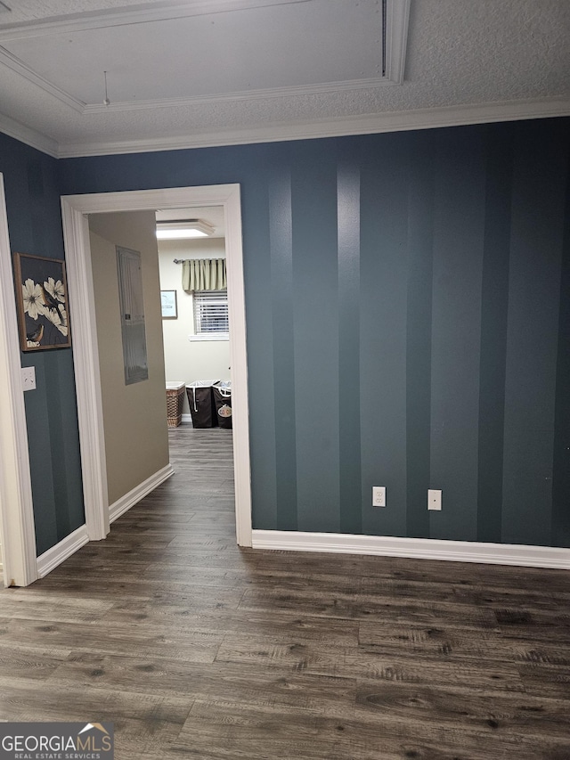 spare room featuring electric panel, attic access, crown molding, baseboards, and dark wood-style floors