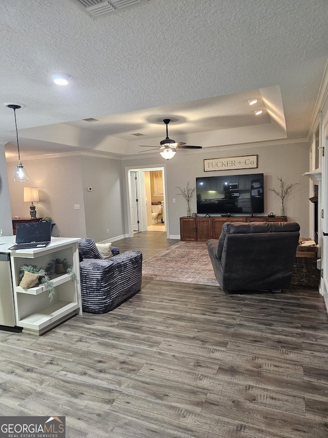 living room with crown molding, a ceiling fan, a textured ceiling, and wood finished floors