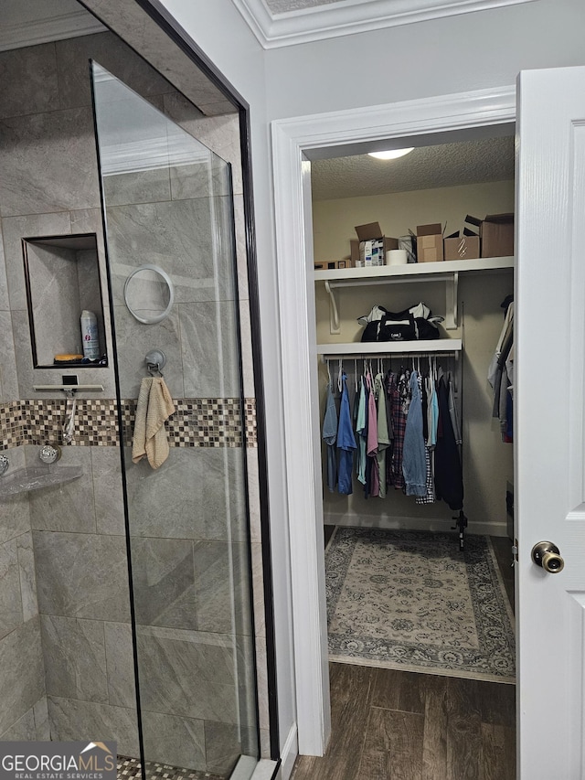 full bath featuring crown molding, a tile shower, and wood finished floors