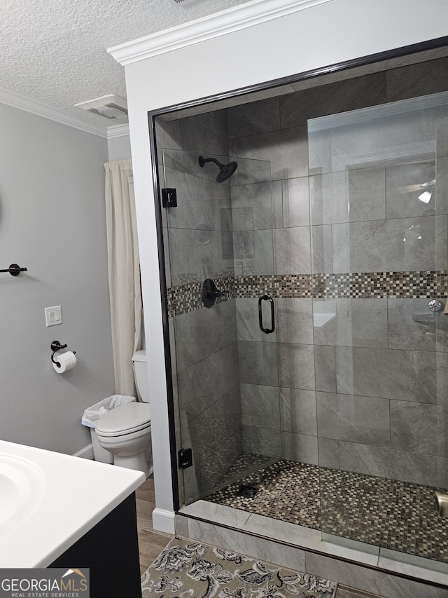 bathroom featuring crown molding, vanity, toilet, a textured ceiling, and a shower stall