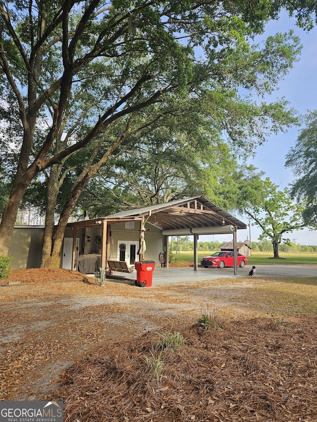 exterior space featuring dirt driveway, french doors, and an attached carport