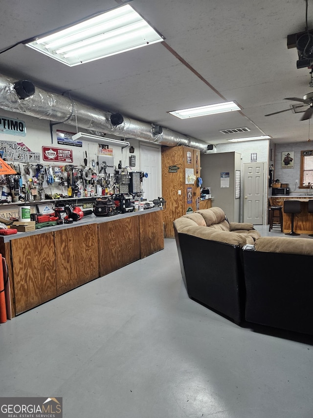 interior space featuring concrete flooring, ceiling fan, a workshop area, and visible vents