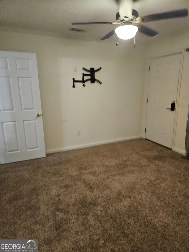 carpeted spare room featuring visible vents, a ceiling fan, and baseboards