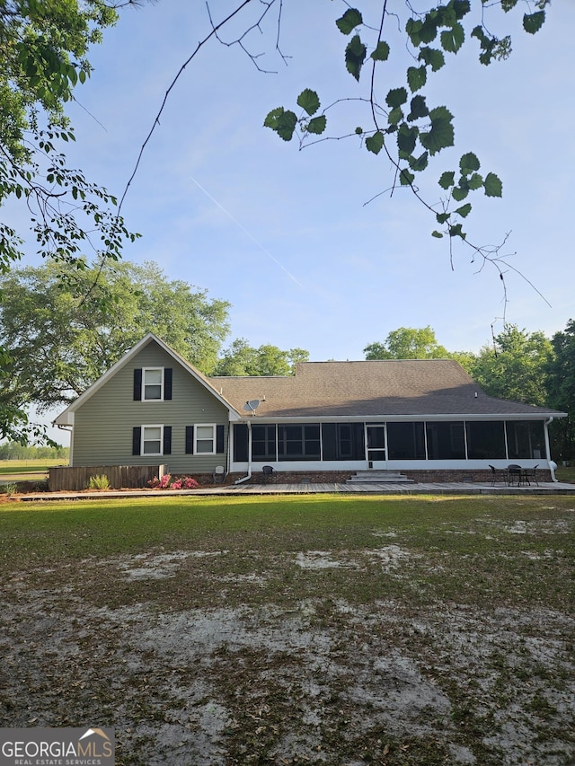 rear view of property featuring a yard and a sunroom