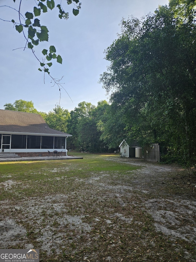 view of yard featuring an outbuilding, a sunroom, and a storage unit