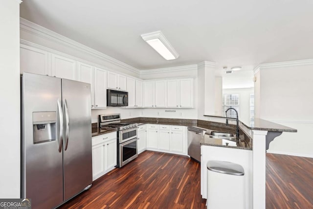 3505 Chattahoochee Summit Ln SE Unit 25, Atlanta, GA 30339 - kitchen with stainless steel appliances, a peninsula, dark wood-style flooring, white cabinets, and ornamental molding