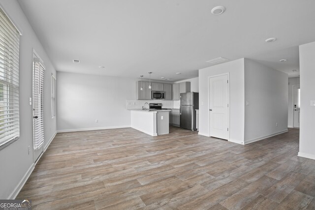unfurnished living room featuring baseboards, a sink, recessed lighting, and light wood-type flooring