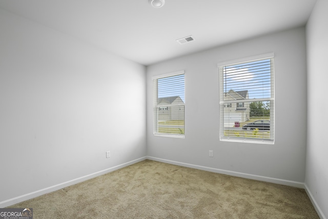 spare room with visible vents, carpet, and baseboards