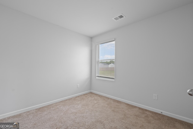 carpeted spare room featuring baseboards and visible vents