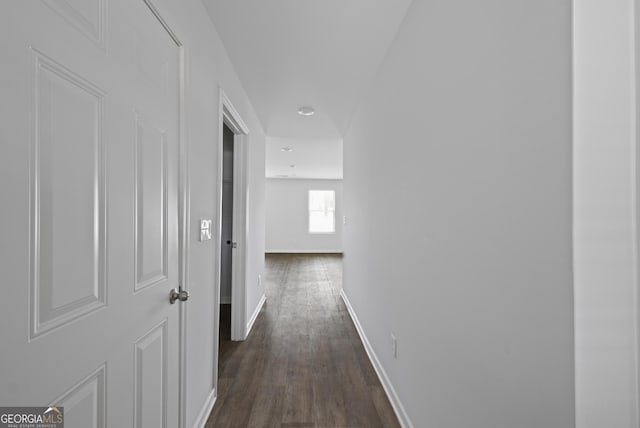 corridor featuring baseboards and dark wood-style floors