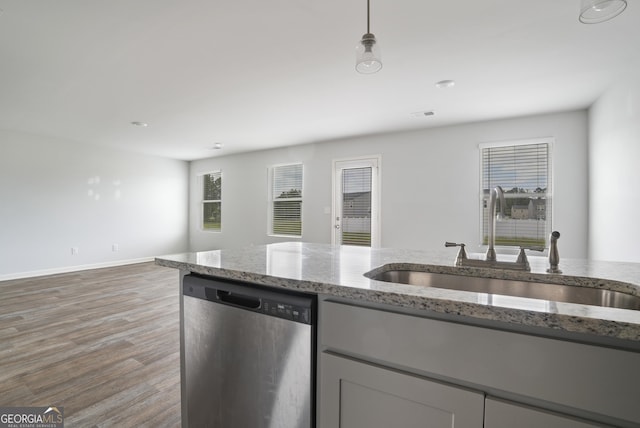 kitchen with stainless steel dishwasher, light stone countertops, baseboards, a sink, and light wood finished floors