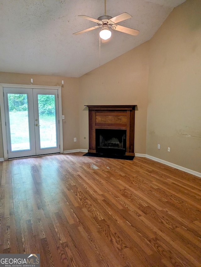unfurnished living room featuring french doors, a ceiling fan, baseboards, wood finished floors, and vaulted ceiling