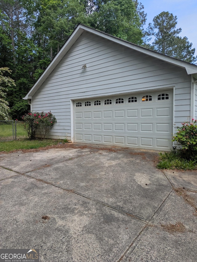 garage featuring fence and driveway