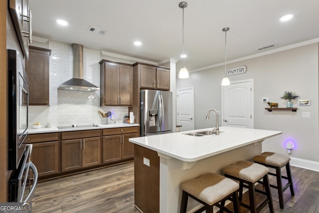 kitchen with stainless steel fridge, wall chimney exhaust hood, a sink, ornamental molding, and black electric stovetop