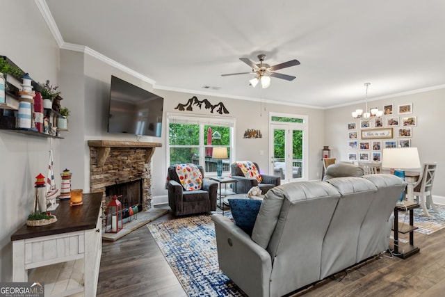 living area with wood finished floors, a ceiling fan, crown molding, a chandelier, and a stone fireplace