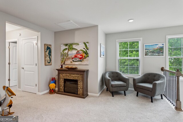 living area with carpet, a stone fireplace, and baseboards