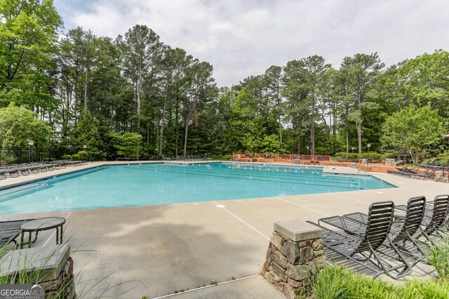 community pool featuring view of scattered trees and a patio