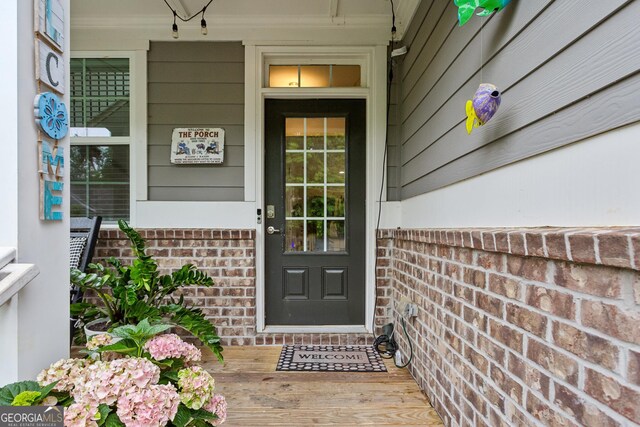 view of exterior entry with covered porch and brick siding