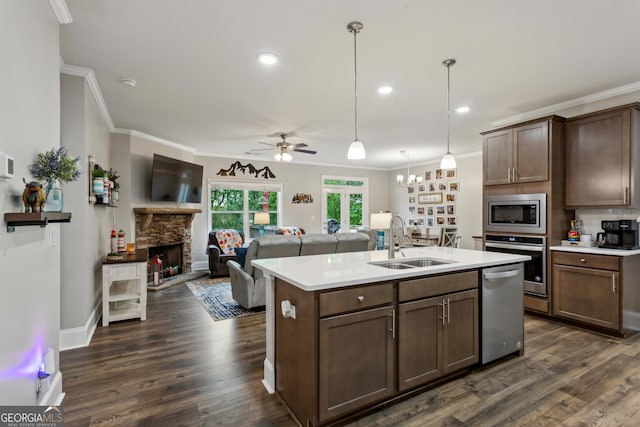 kitchen with a sink, stainless steel appliances, light countertops, ornamental molding, and dark wood-style flooring