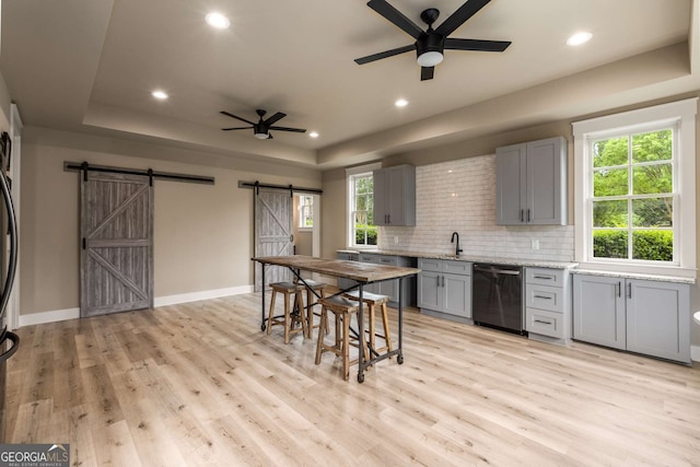 2855 Drayton Hall Dr, Buford, GA 30519 - kitchen featuring dishwashing machine, a ceiling fan, a tray ceiling, a barn door, and gray cabinetry