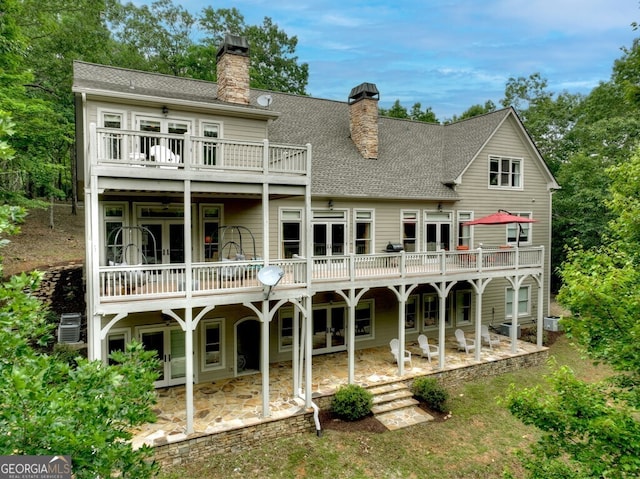 rear view of property featuring french doors, a chimney, a patio area, and a balcony