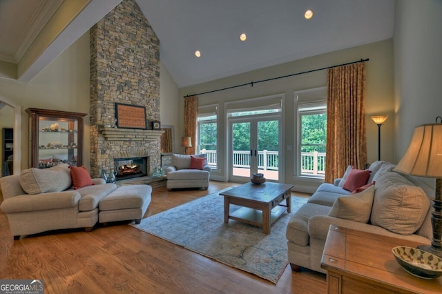 living area with a fireplace, high vaulted ceiling, french doors, wood finished floors, and ornamental molding