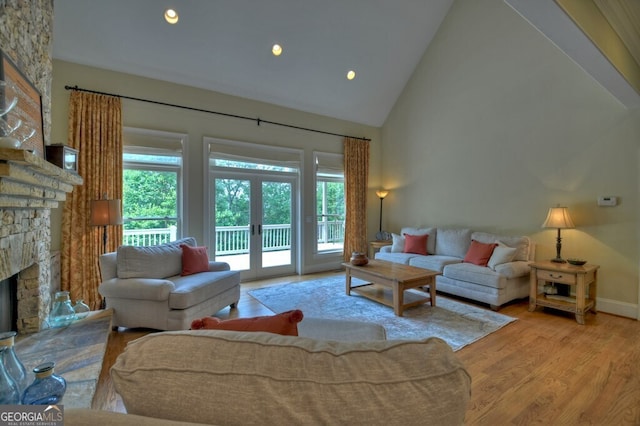 living room featuring high vaulted ceiling, a stone fireplace, french doors, recessed lighting, and wood finished floors