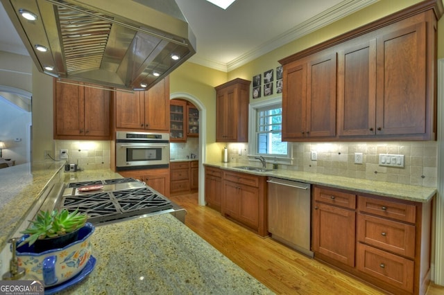 kitchen with crown molding, appliances with stainless steel finishes, ventilation hood, arched walkways, and light wood-type flooring