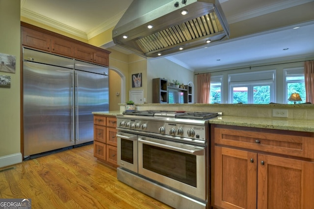 kitchen with ornamental molding, premium appliances, light wood-style flooring, and extractor fan