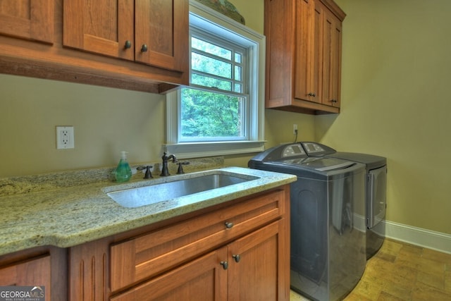 laundry room featuring baseboards, a sink, cabinet space, and washer and dryer