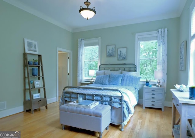 bedroom with visible vents, baseboards, wood finished floors, and multiple windows