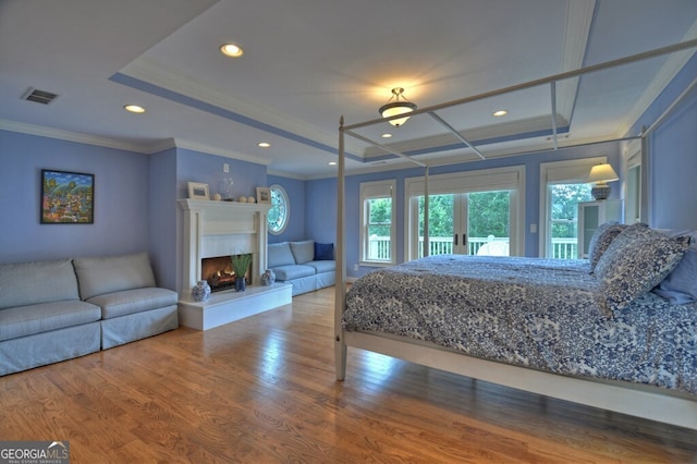 bedroom featuring crown molding, a warm lit fireplace, access to exterior, wood finished floors, and visible vents