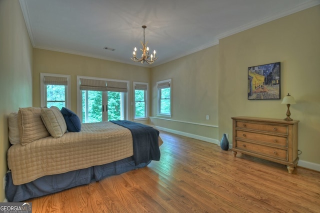 bedroom featuring baseboards, ornamental molding, wood finished floors, and a notable chandelier